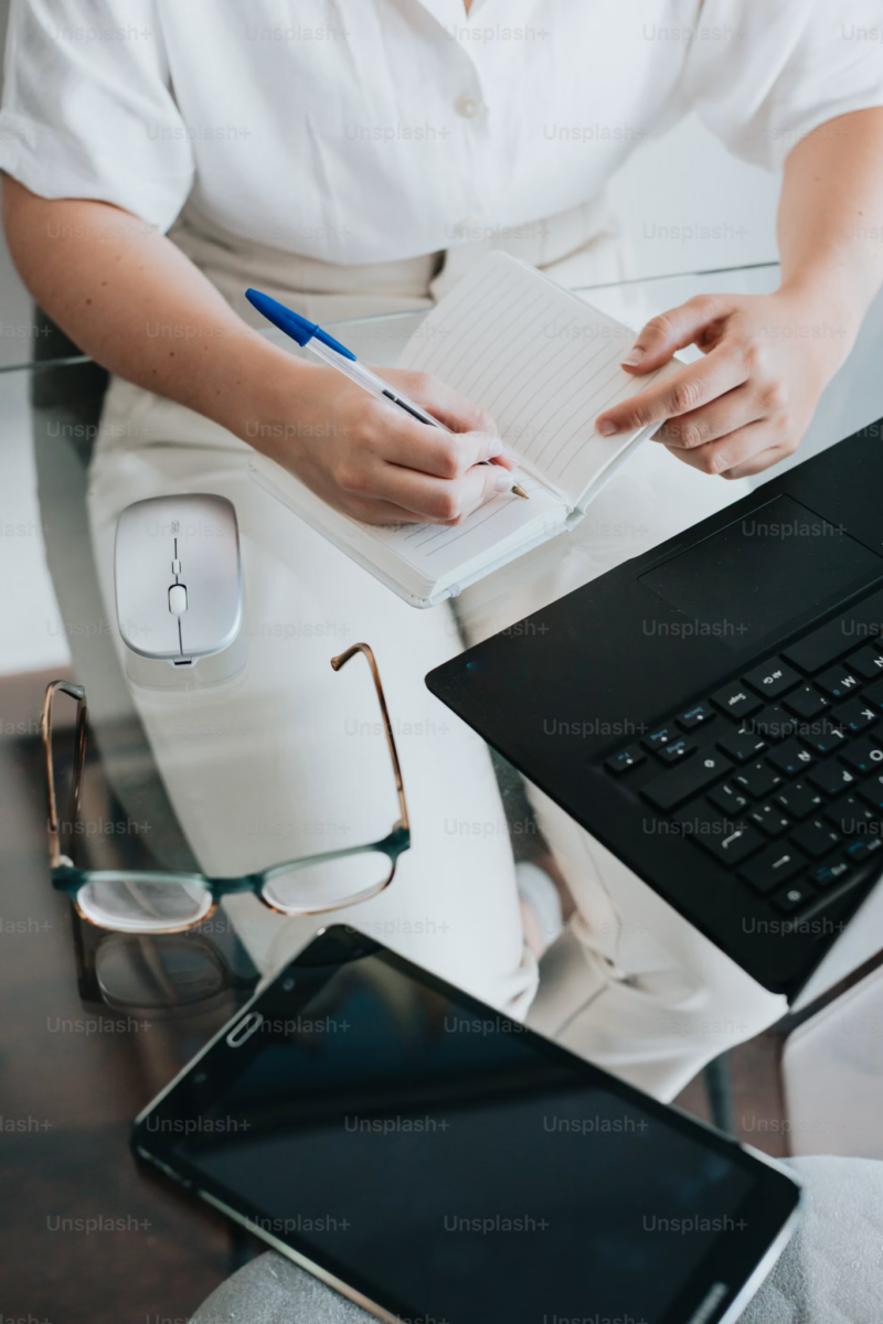 Person working remotely on a laptop at a desk with mouse and notebook.